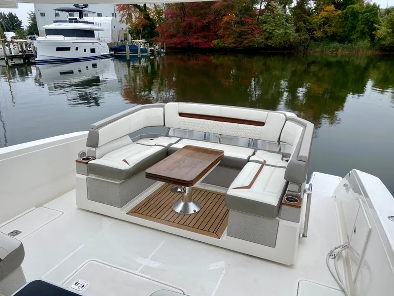Slide: The Image of 2022 Tiara Yachts 38 LS with elegant seating and table on a serene waterfront. - 13