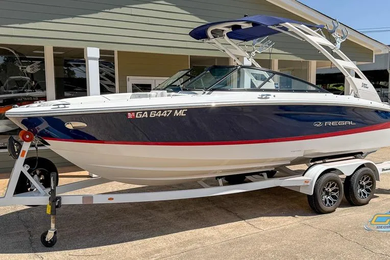 Slide: The Image of 2022 Regal LS2 Surf boat on trailer, blue and white design, parked outdoors. - 10