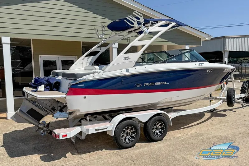 Slide: The Image of 2022 Regal LS2 Surf boat on trailer, parked outside a building. - 2
