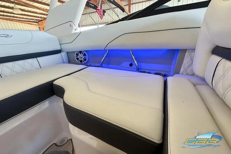 Slide: The Image of 2022 Regal LS2 Surf boat interior with white seating, blue LED lighting, and cup holders. - 21
