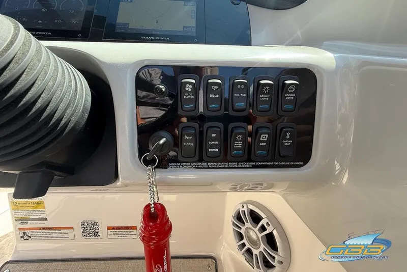 Slide: The Image of Control panel of 2022 Regal LS2 Surf boat with various switches and keychain. - 36