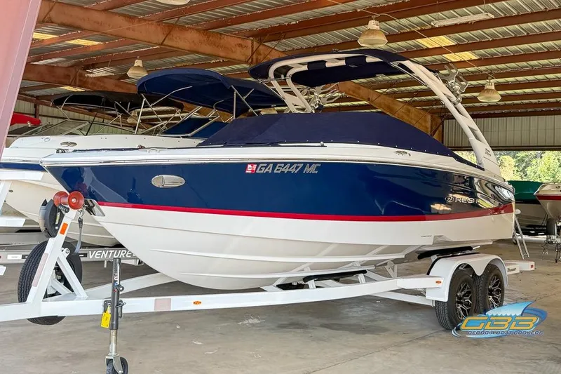 Slide: The Image of 2022 Regal LS2 Surf boat in storage, blue and white design, on a trailer. - 49