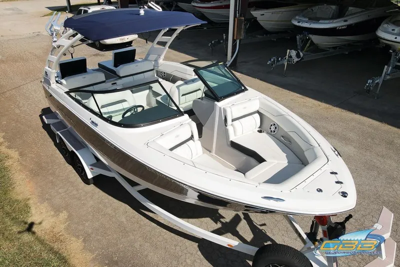 Slide: The Image of 2022 Regal LS2 Surf boat with sleek design and spacious seating, parked on a trailer. - 5