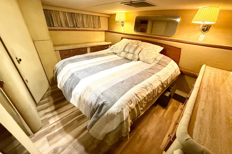 Slide: The Image of Cozy bedroom interior of 1982 Chris-Craft 410 Motor Yacht with striped bedding and warm lighting. - 11