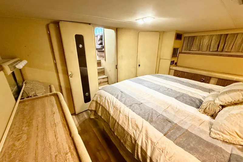 Slide: The Image of 1982 Chris-Craft 410 Motor Yacht bedroom with striped bedding and wooden furnishings. - 12