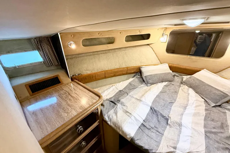 Slide: The Image of 1982 Chris-Craft 410 Motor Yacht bedroom with striped bedding and wooden cabinetry. - 16