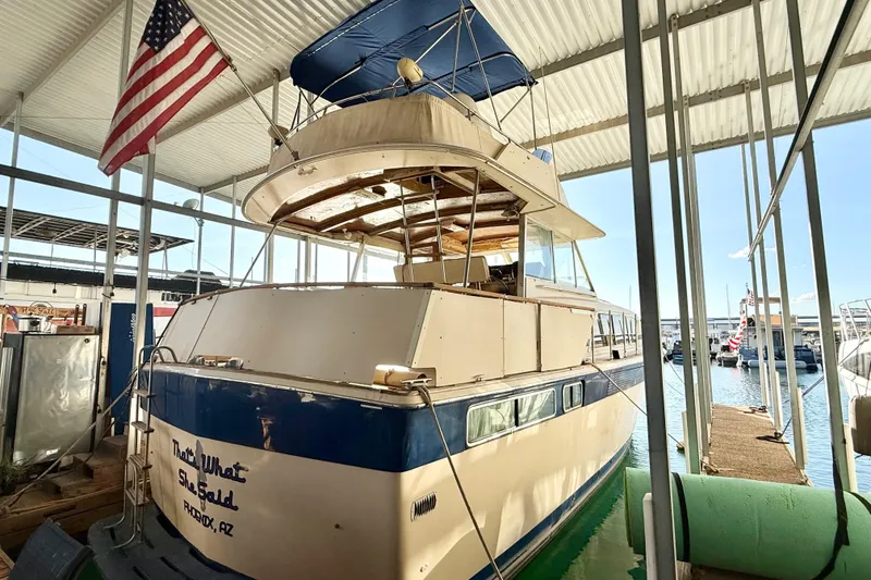 Slide: The Image of 1982 Chris-Craft 410 Motor Yacht docked under a covered marina with American flag. - 4