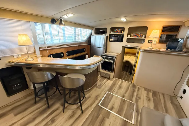 Slide: The Image of 1982 Chris-Craft 410 Motor Yacht interior with kitchen, bar seating, and cozy lighting. - 7