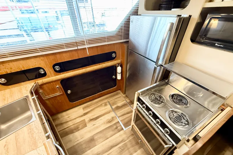 Slide: The Image of 1982 Chris-Craft 410 Motor Yacht kitchen with stove, fridge, and wooden cabinetry. - 8