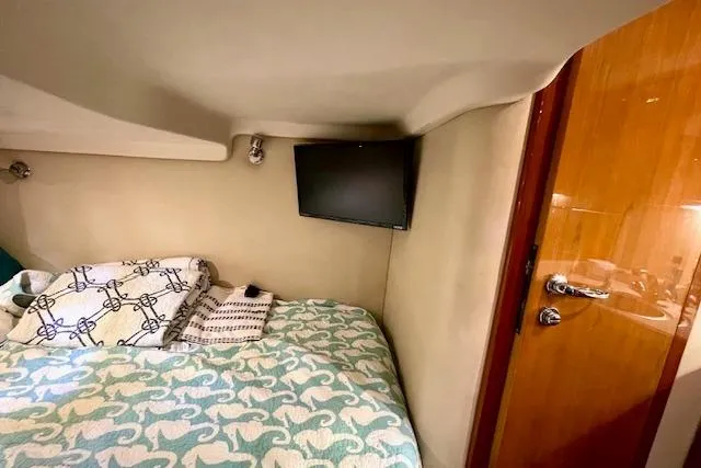 Slide: The Image of 2005 Regal Commodore 4260 cabin interior with bed, TV, and wooden door. - 47