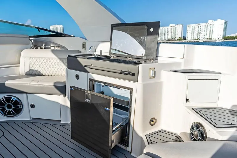 Slide: The Image of 2021 Sea Ray 350 SLX OB yacht interior with open fridge and luxurious seating. - 24