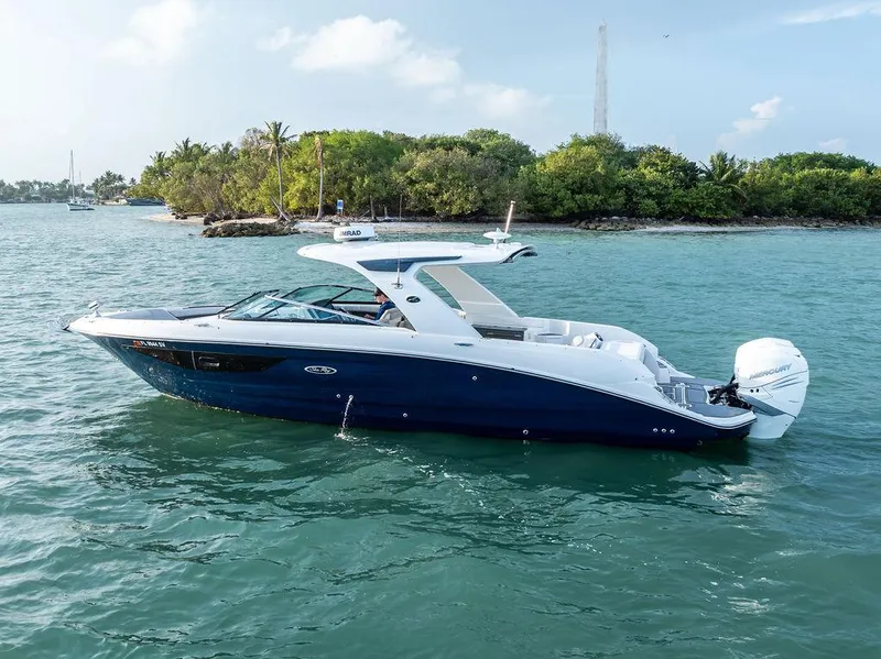 Slide: The Image of 2021 Sea Ray 350 SLX OB boat cruising on turquoise water near lush island. - 5