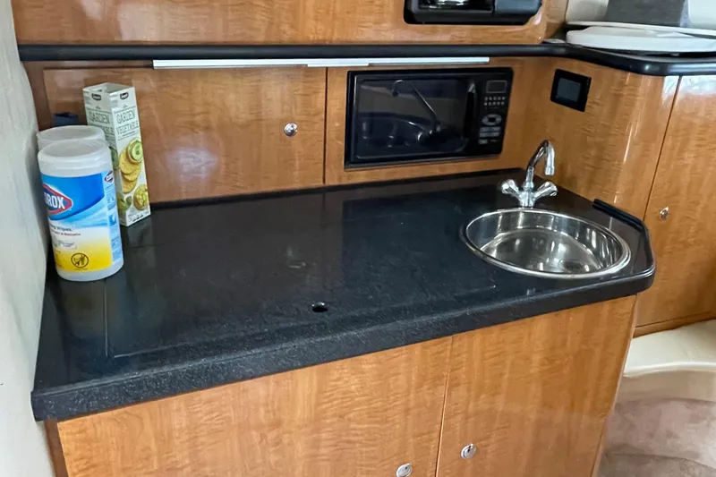 Slide: The Image of 2003 Regal Commodore 3060 kitchenette with sink, microwave, and cleaning supplies. - 17