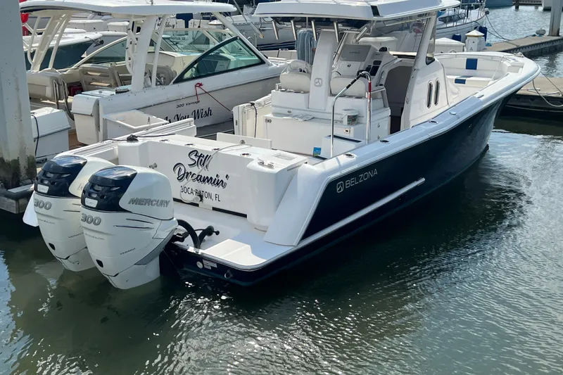 Slide: The Image of 2017 Belzona 325 Center Console boat on calm water, near a forested shoreline. - 15