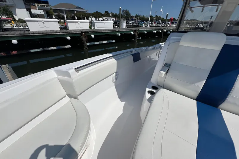 Slide: The Image of 2017 Belzona 325 Center Console boat interior with white and blue seating at a marina. - 41