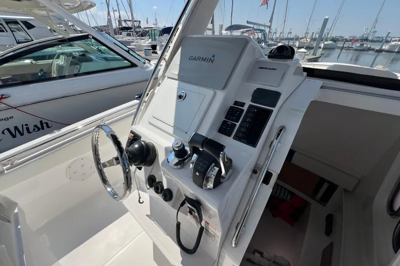 Slide: The Image of 2017 Belzona 325 Center Console helm with Garmin and Mercury controls at marina. - 42