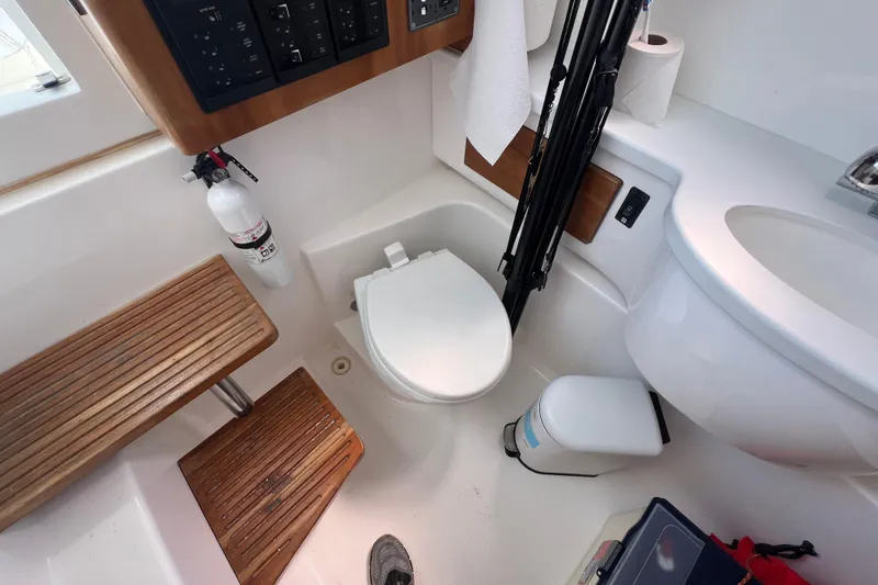 Slide: The Image of 2017 Belzona 325 Center Console boat bathroom with toilet, wooden steps, and fire extinguisher. - 46