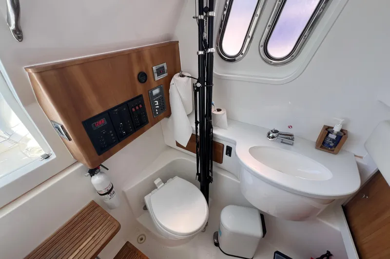 Slide: The Image of Interior of 2017 Belzona 325 Center Console boat bathroom with sink, toilet, and control panel. - 48