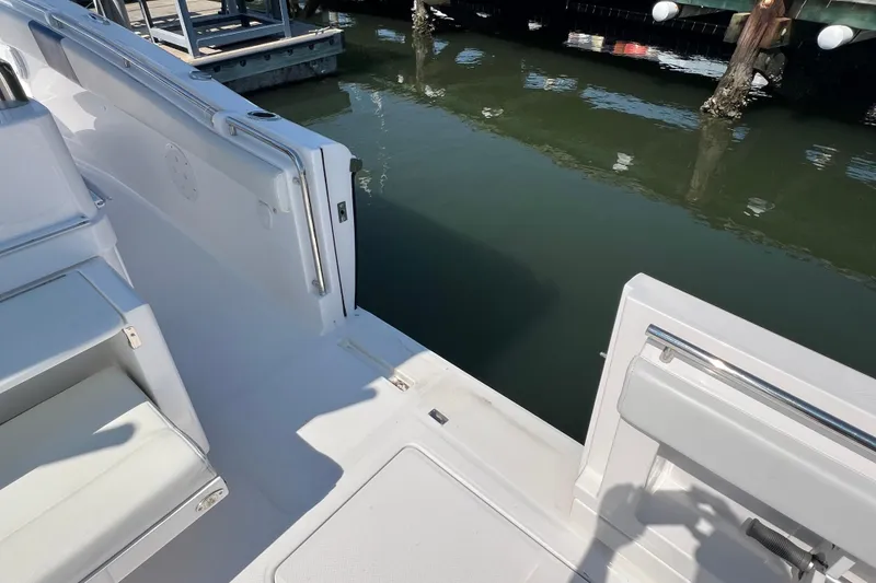 Slide: The Image of 2017 Belzona 325 Center Console boat docked, showing open side door and seating area. - 65