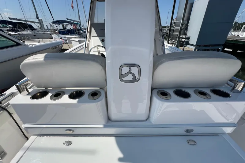 Slide: The Image of 2017 Belzona 325 Center Console boat interior with seating and cup holders at a marina. - 76