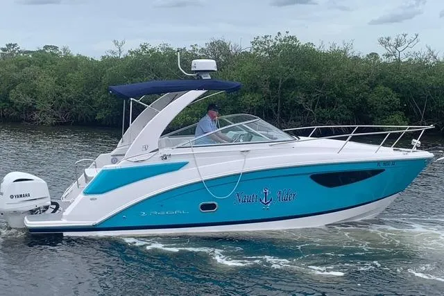The Image of 2021 Regal 26 XO boat cruising on water with lush greenery in the background. - 0