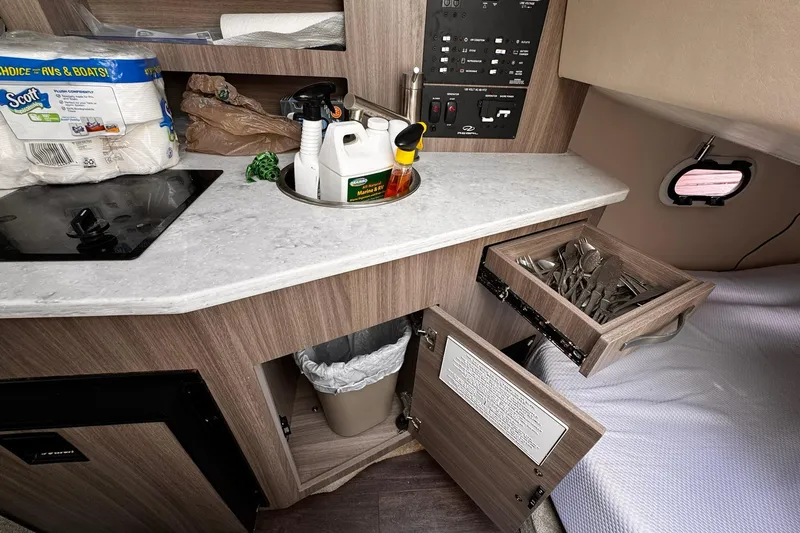 Slide: The Image of 2021 Regal 26 XO boat interior with kitchenette, utensils, and cleaning supplies. - 18