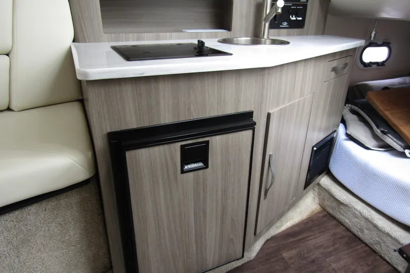 Slide: The Image of 2021 Regal 26 XO boat interior kitchenette with sink, stove, and compact refrigerator. - 33