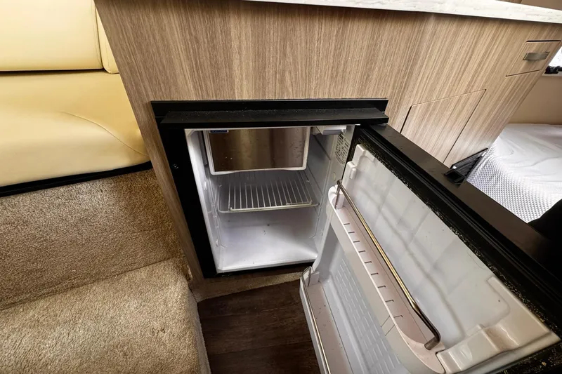 Slide: The Image of Open mini fridge inside 2021 Regal 26 XO boat cabin, showcasing compact storage space. - 34