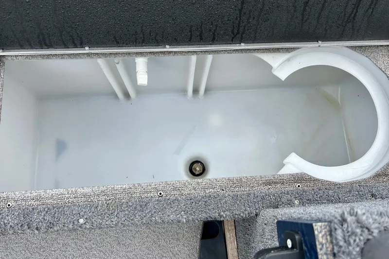 Slide: The Image of Open storage compartment in 2018 Crestliner CVN16 boat, featuring a white interior and drainage plug. - 20