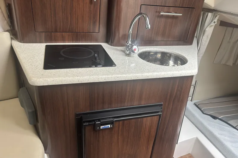 Slide: The Image of Compact kitchen area in 2016 Regal 28 Express boat with sink, stove, and fridge. - 7