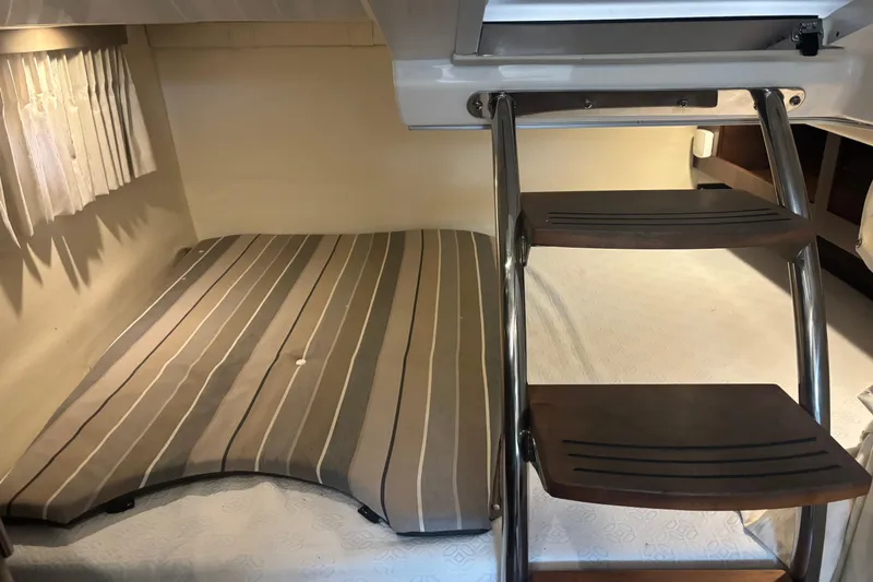 Slide: The Image of 2016 Regal 28 Express cabin interior with striped bedding and wooden ladder steps. - 9