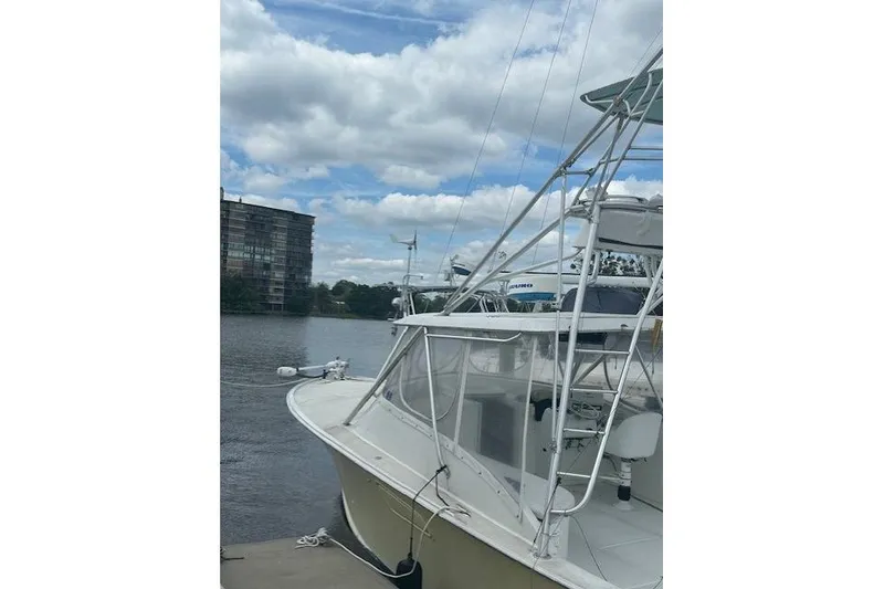 Slide: The Image of 2002 Bob Sherbert and Lou Rambo Custom Sportfish boat docked by a river under cloudy skies. - 1