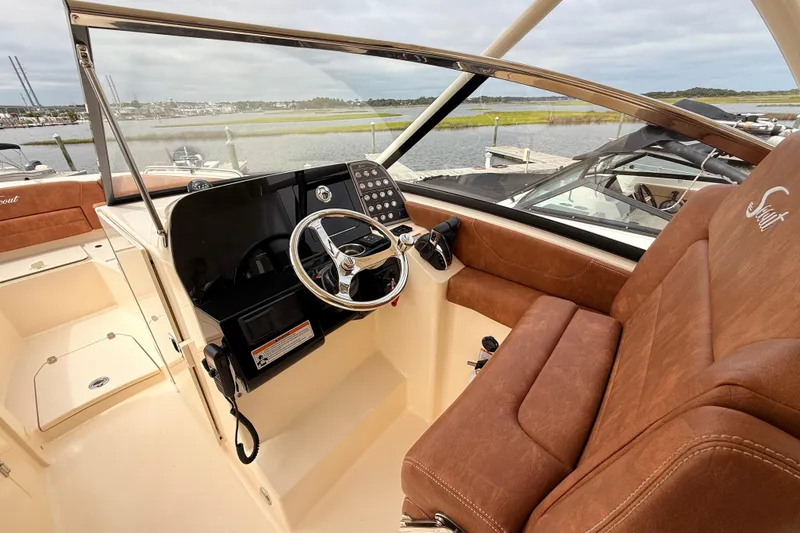 Slide: The Image of 2023 Scout 255 Dorado boat interior with brown leather seating and modern dashboard. - 21