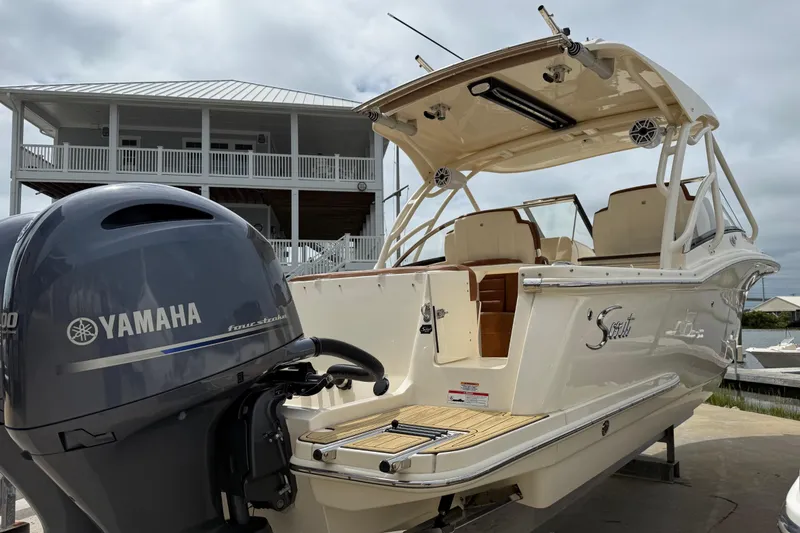 Slide: The Image of 2023 Scout 255 Dorado boat with Yamaha engine, docked near a waterfront house. - 4