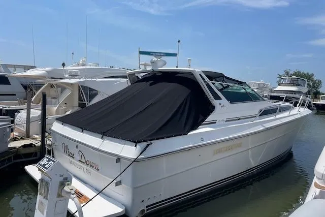 Slide: The Image of 1989 Sea Ray 390 Express Cruiser docked at marina, covered with black tarp. - 1