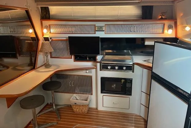 Slide: The Image of 1989 Sea Ray 390 Express Cruiser interior with kitchen, bar stools, and appliances. - 8