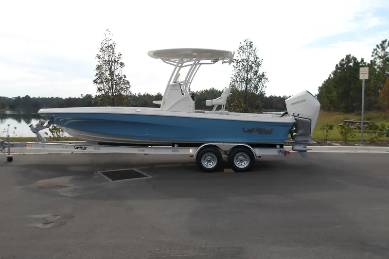 Slide: The Image of 2026 Mako 24 APEX boat on trailer, parked near a scenic lake. - 15