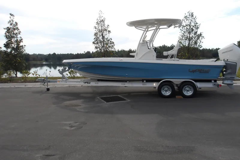 Slide: The Image of 2026 Mako 24 APEX boat on trailer by a scenic lake. - 16
