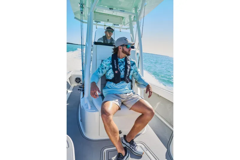 Slide: The Image of Man organizing fishing rods on Mako 24 APEX boat, 2026 model, under clear blue sky. - 94