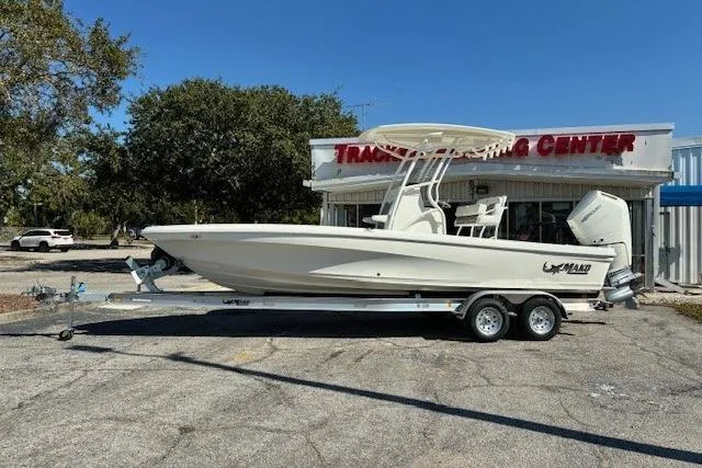 Slide: The Image of 2026 Mako 24 APEX boat on trailer with fishing rods and motor. - 2
