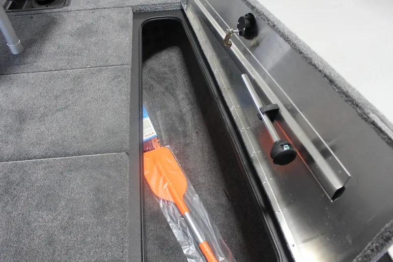 Slide: The Image of 2026 Tracker Pro Team 195 boat storage compartment with orange paddle and rod holder. - 13