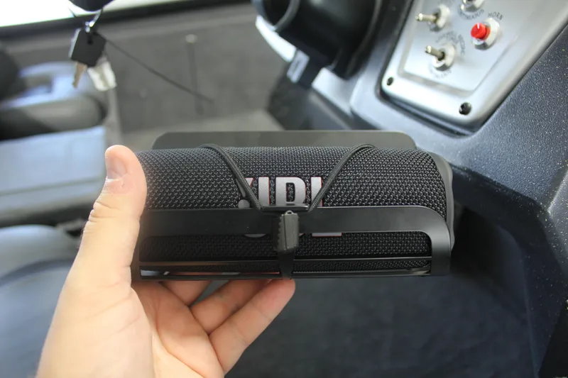 Slide: The Image of Hand holding a portable speaker inside a 2026 Tracker Pro Team 195 boat. - 20