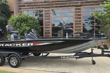 The Image of 2026 Tracker Pro Team 195 boat on trailer, parked outdoors near a building. - 0