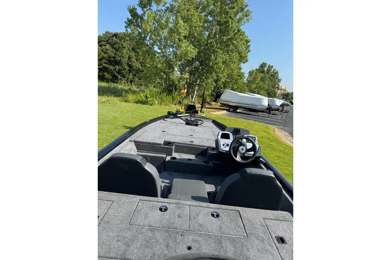 Slide: The Image of 2026 Tracker Pro Team 195 boat interior with steering wheel, parked on grass. - 5