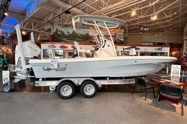 Slide: The Image of 2026 Mako 24 APEX boat displayed in showroom, featuring sleek design and dual-axle trailer. - 2
