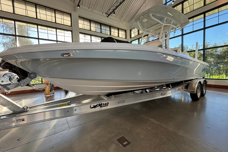 The Image of 2026 Mako 24 APEX boat on trailer in showroom with large windows. - 0