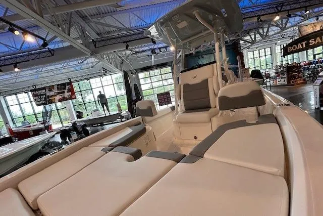 Slide: The Image of 2026 Mako 24 APEX boat interior with cushioned seating in a showroom. - 6
