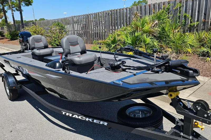 Slide: The Image of 2026 Tracker Panfish 17 fishing boat on trailer, parked near greenery. - 2