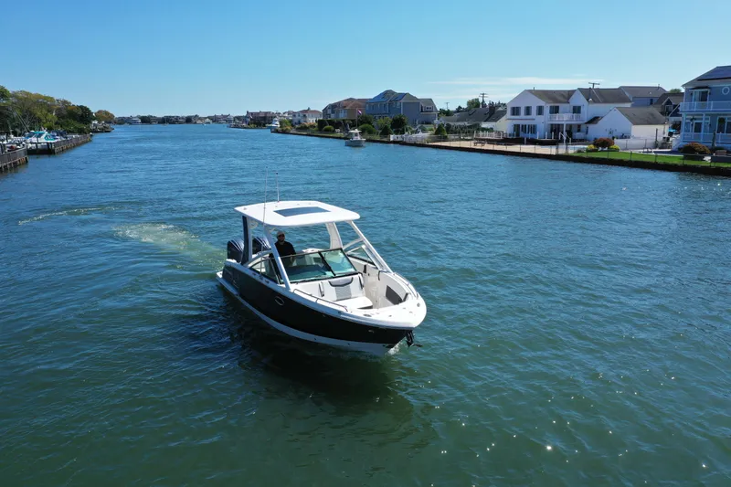 Slide: The Image of Chaparral 280 OSX 2022 boat cruising on a sunny waterfront with houses in the background. - 3