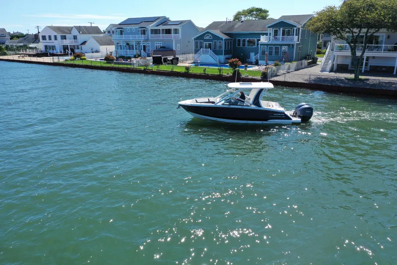 Slide: The Image of 2022 Chaparral 280 OSX boat cruising on a sunny waterfront near modern homes. - 38